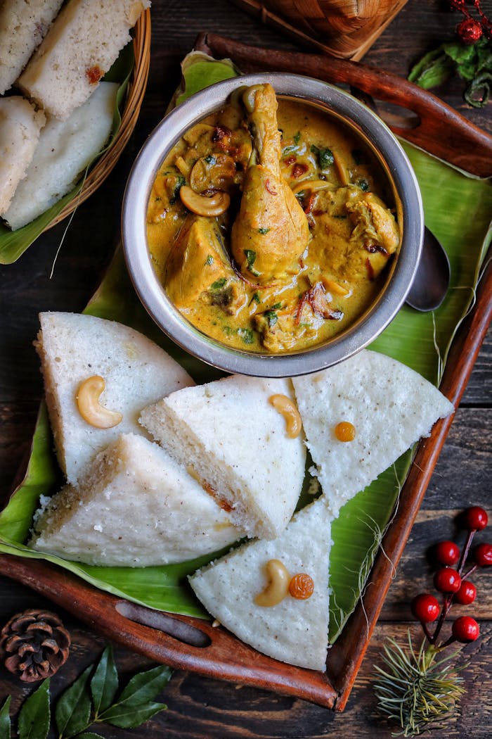 Delicious South Indian chicken curry with cashews, served with soft idli on a banana leaf.