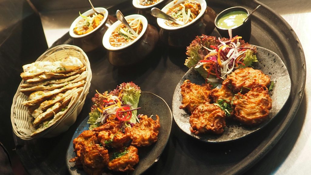A flavorful assortment of Indian cuisine with various dishes on a serving tray, highlighting vibrant spices and textures.